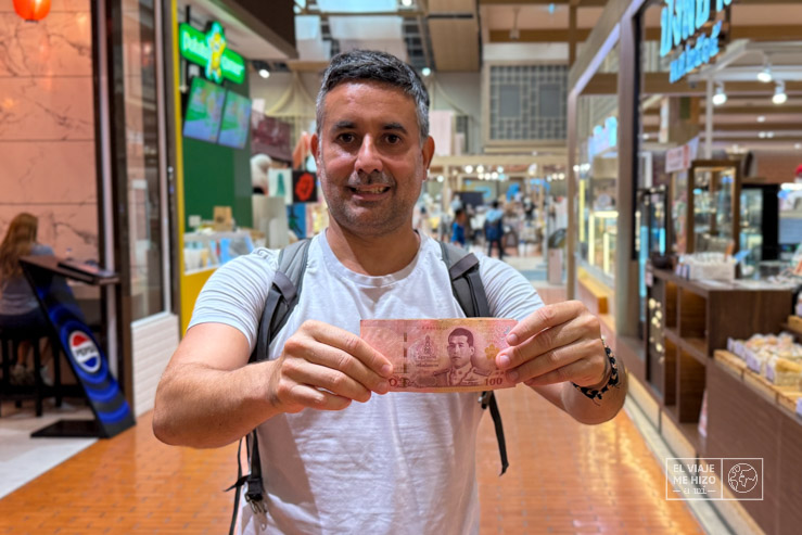 Jose con 100 bahts pensando en el presupuesto para viajar a Tailandia